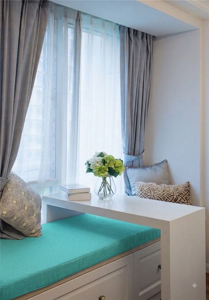 A bay window bench seat with a bright teal woven cushion, styled with patterned throw pillows