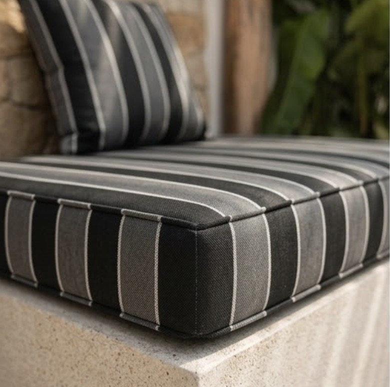 Close-up of the charcoal and cream striped Sunbrella fabric, showing the weave and corner seam of a box cushion