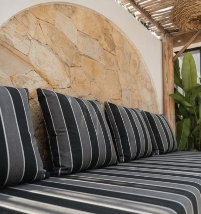 A row of striped throw pillows against a stone archway, angled view of the bench cushion